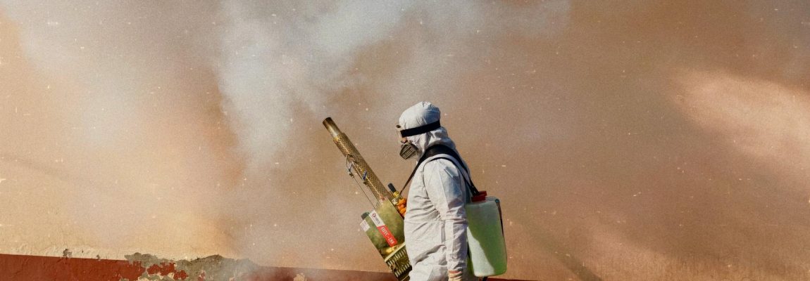A worker in protective gear sprays pesticide inside a house for fumigation.