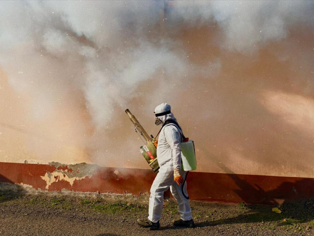 A professional pest control worker in protective gear fumigating an office space.