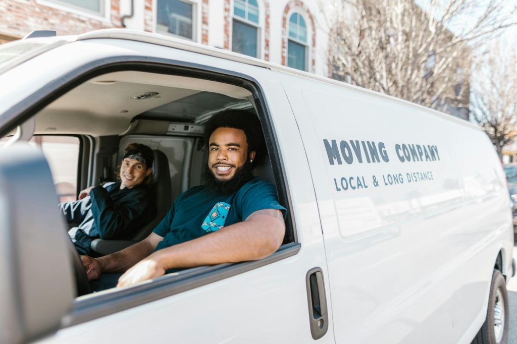 Professional moving team in blue uniforms carrying a large office filing cabinet up a staircase for relocation.