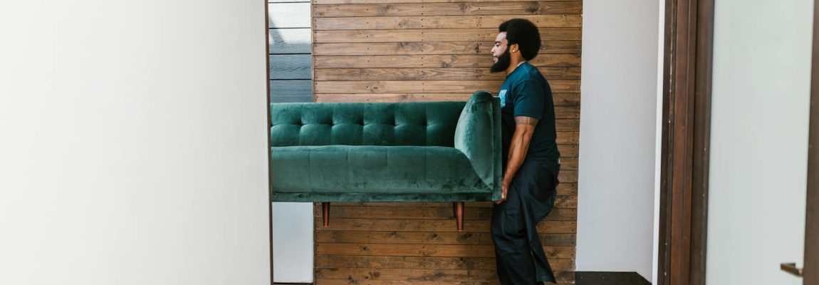 Professional furniture movers in Kenya carrying a sofa through a home.