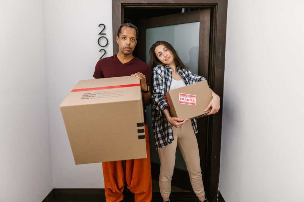 A smiling man in a yellow shirt stands next to a large moving truck, ready for relocation in Kenya.