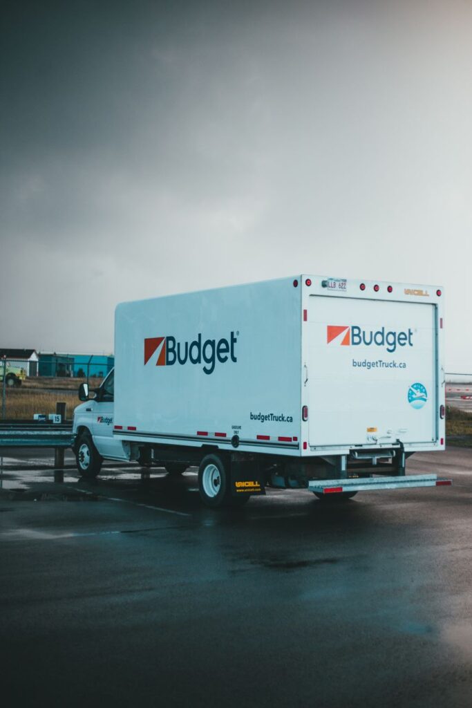 A moving truck parked in front of a house with boxes and furniture being loaded for relocation.