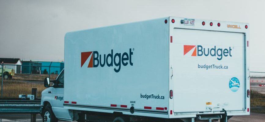 Two movers carrying furniture into a moving truck for a residential relocation.