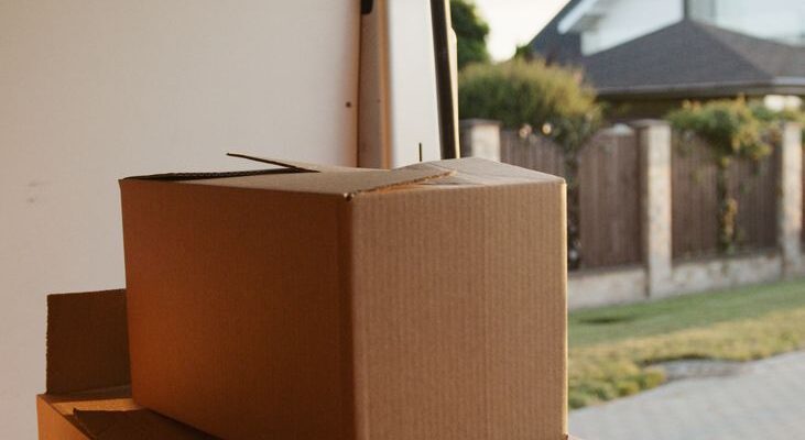 A moving truck and a stack of cardboard boxes with household items, ready for relocation.