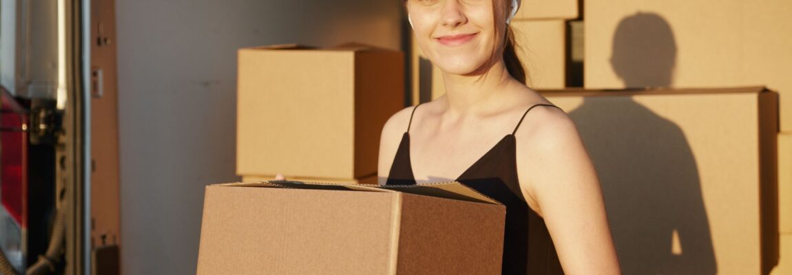 Professional movers carrying furniture boxes near a rental truck.