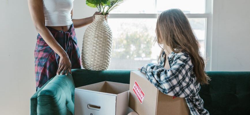 Movers carrying furniture out of a house, loading items into a truck for a local move.
