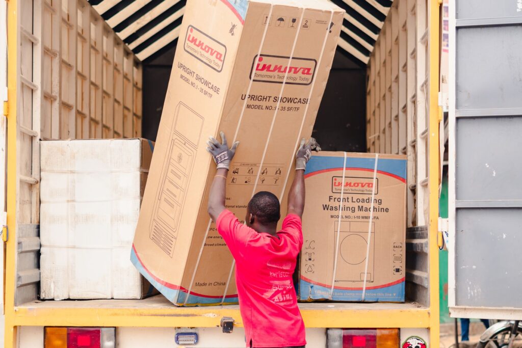 moving services syokimau - A moving truck with workers loading boxes outside a home in Syokimau, with contact number 07298397
